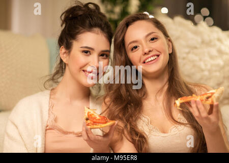 happy female friends eating pizza at home Stock Photo