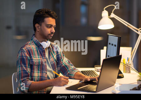 creative man with laptop working at night office Stock Photo