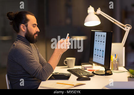 creative man with smartphone at night office Stock Photo