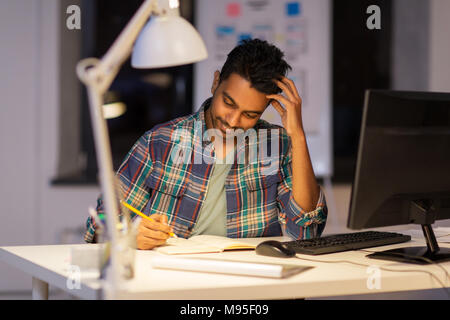 creative man with notebook working at night office Stock Photo