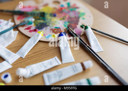 Artist paint brushes and oil paint tubes on wooden palette