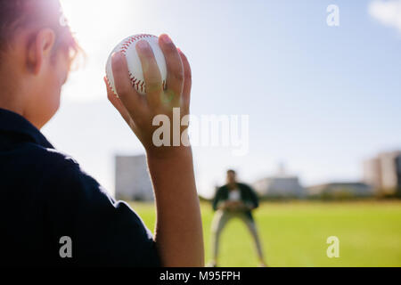 Rear view close up of a boy throwing baseball at a man in a ground. Boy playing with a baseball along with his father. Stock Photo