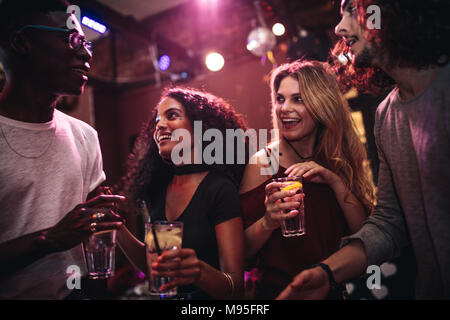 Diverse group of young people with drinks in a club. Happy men and women enjoying nightout at bar. Stock Photo