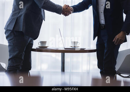 Two businessmen shaking hands after successful meeting. Businesspeople handshake after a deal. Cropped shot with focus on hands. Stock Photo