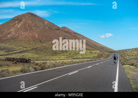People cycling on road bikes on an empty road through theTimanfaya National Park in Lanzarote Stock Photo