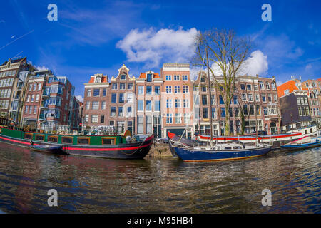 AMSTERDAM, NETHERLANDS, MARCH, 10 2018: Exterior shot of houseboats and apartment buildings on a canal in the city of Amsterdam Stock Photo