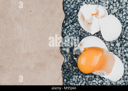 Broken egg on gray gravel, asphalt. The risk of loss, ruin. Stock Photo