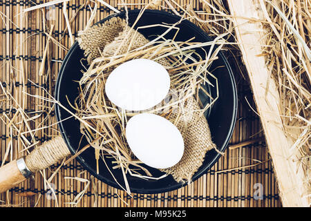 Two whole eggs in a cast iron frying pan on a wooden table. Cooking eggs. Stock Photo
