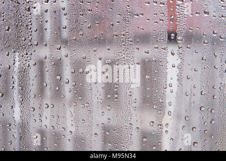 Rain drops on the window reflecting houses on the street outside in every drop Stock Photo