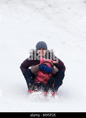Grandmother looks scared and grand-daughter covers her eyes while sledging in Quebec, Canada Stock Photo
