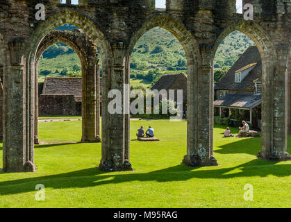 Relaxing in the sun in the ruins of Llanthony Priory in the Llanthony Valley of the Brecon Beacons in South Wales UK Stock Photo