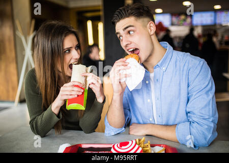 Young couple in a fast food restaurant eating hamburger Stock Photo
