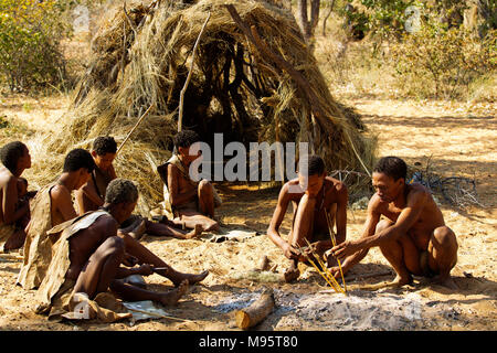 Ju/'Hoansi or San bushmen in daily activities making bow and arrows at their village, Grashoek, Namibia Stock Photo