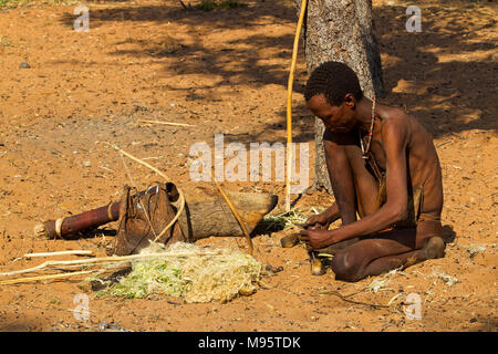 Ju/'Hoansi or San bushmen in daily activities making bow and arrows at their village, Grashoek, Namibia Stock Photo