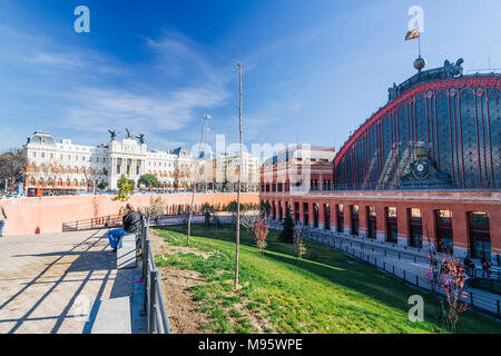 Madrid, Spain : Front view of Atocha train Station and passersby at Plaza del Emperador Carlos V (Emperor Charles V Square) inaugurated in 1851 with t Stock Photo