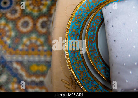 A closeup of table setting in muslim restaurant, tablecloth, plates and napkin all with arabic design, Morocco. Stock Photo