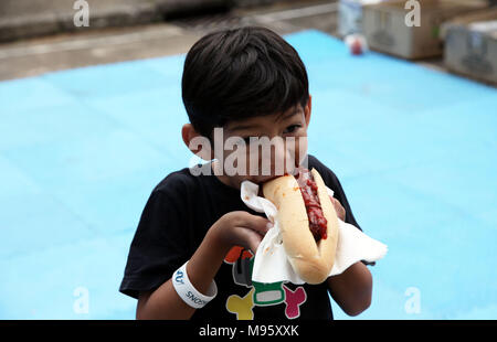 Little HUngry Eurasian Boy Eating a Hot-dog with appetite Stock Photo