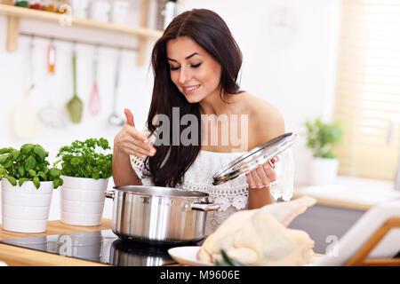 Young woman trying to prepare chicken soup in kitchen Stock Photo