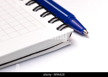 Blue ball pen on blank note book on white background. Close-up macro view Stock Photo