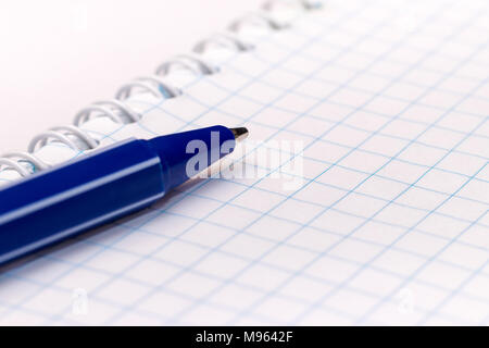 Blue ball pen on blank note book on white background. Close-up macro view Stock Photo