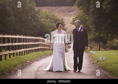 Newly married couple walking up country lane together Stock Photo