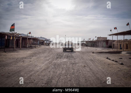 HMMWVs of the Afghan Commandos driving through an empty part of Farahrud Bazaar, Bolo Bluk district, Farah province, Afghanistan (7th of March 2018). Despite the many Afghan national flags on the rooftops, the area is a Taliban stronghold. Later that night, the Commandos had to retreat via the same street after a failed operation to retake the nearby village from insurgents. Afghanistan’s elite military forces – the Commandos and the Special Forces are one of the key elements in the Afghan and U.S. strategy to turn the grinding fight against the Taliban and other insurgents around. These pictu Stock Photo