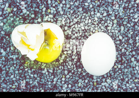 Broken egg on gray gravel, asphalt. The risk of loss, ruin. Stock Photo
