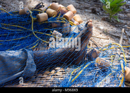 Man on Uzi Island, Zanzibar, mending  fishing nets by hand at the beach front Stock Photo