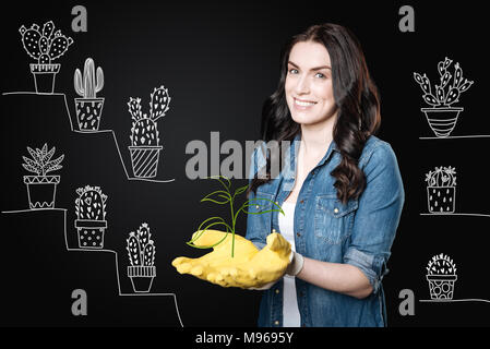 Positive gardener wearing rubber gloves while working with plants Stock Photo