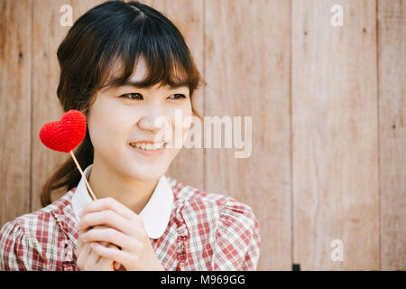 Cute young asia woman hold red heart on wooden background vintage colortone Stock Photo