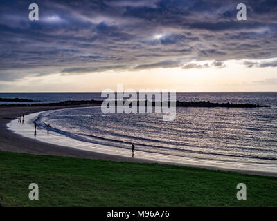 An evening stroll along the beach with some colourful light on the clouds. Stock Photo