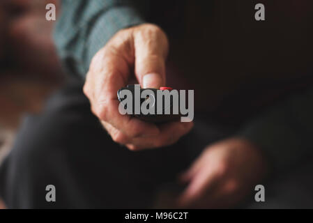 closeup of an old caucasian man sitting in a couch using a remote control Stock Photo