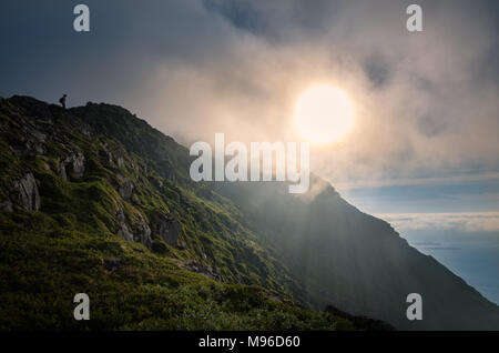 Mountain landscape from top of the peak with hiker at evening light in Lofoten Islands, Norway Stock Photo