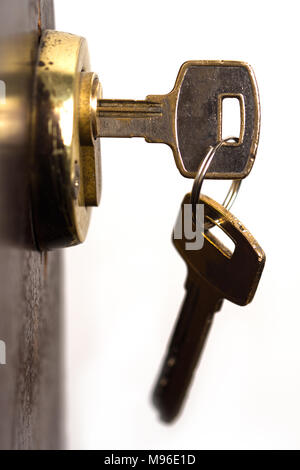 vertical closeup of pair of keys in metallic golden door lock Stock Photo