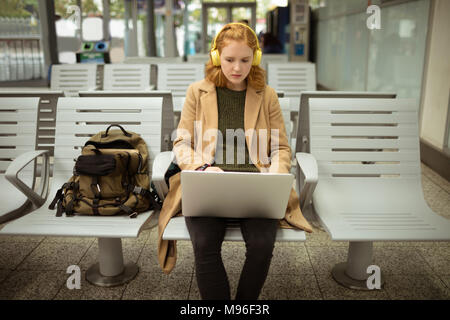 Young woman listing to music while working on laptop Stock Photo