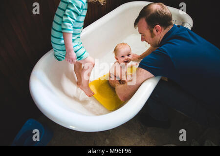 Father washing baby in tub with other girl Stock Photo