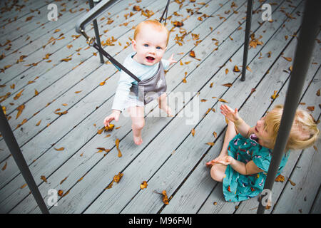 Baby smiling and jumping with girl watching Stock Photo