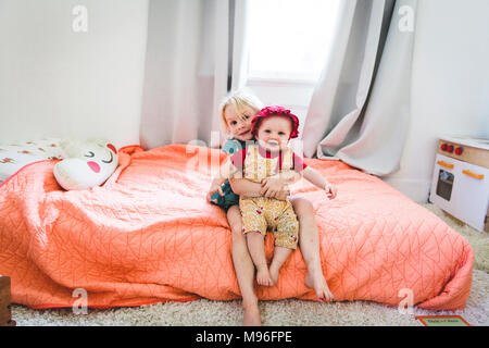 Girl holding baby on bed Stock Photo