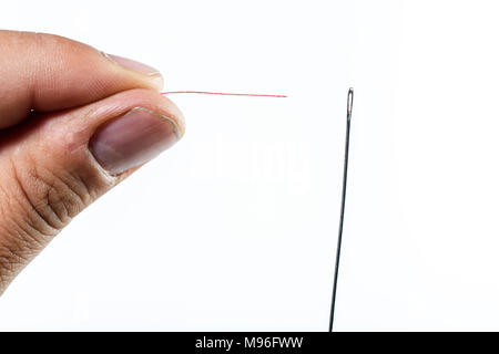 hand of man threading a needle with red thread on white background Stock Photo