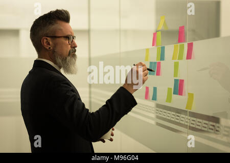 Business executive writing on sticky notes Stock Photo