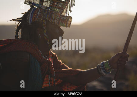 Maasai man in traditional clothing sitting at countryside Stock Photo