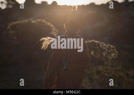Maasai man in traditional clothing standing with stick Stock Photo