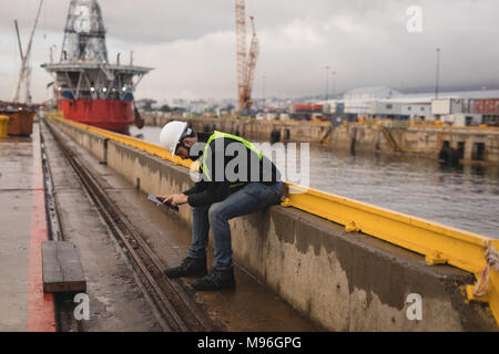 Dock worker using mobile phone Stock Photo