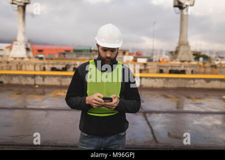Dock worker using mobile phone Stock Photo