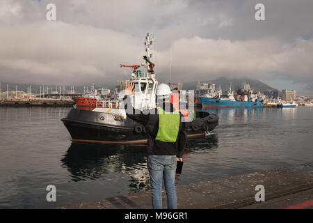 Dock worker waving hand to sailing boat Stock Photo