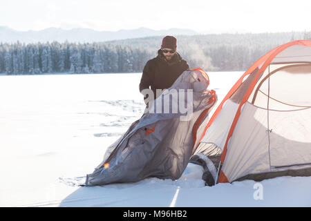 Man pitching a tent in snowy landscape Stock Photo