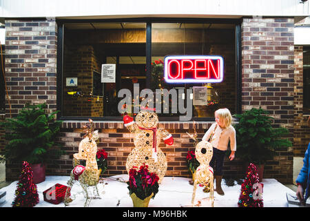 Girl with Christmas decorations next to open restaurant Stock Photo