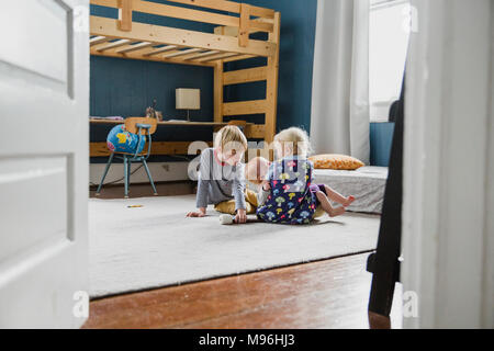 Two children and baby sitting in bedroom Stock Photo