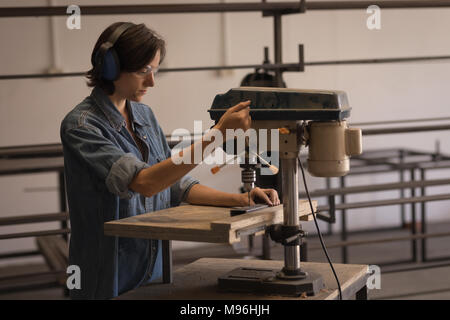 Female welder using vertical drilling machine Stock Photo