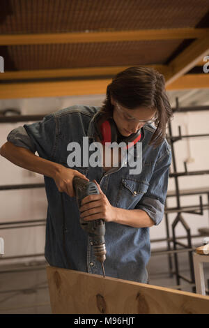Female welder using drilling machine Stock Photo